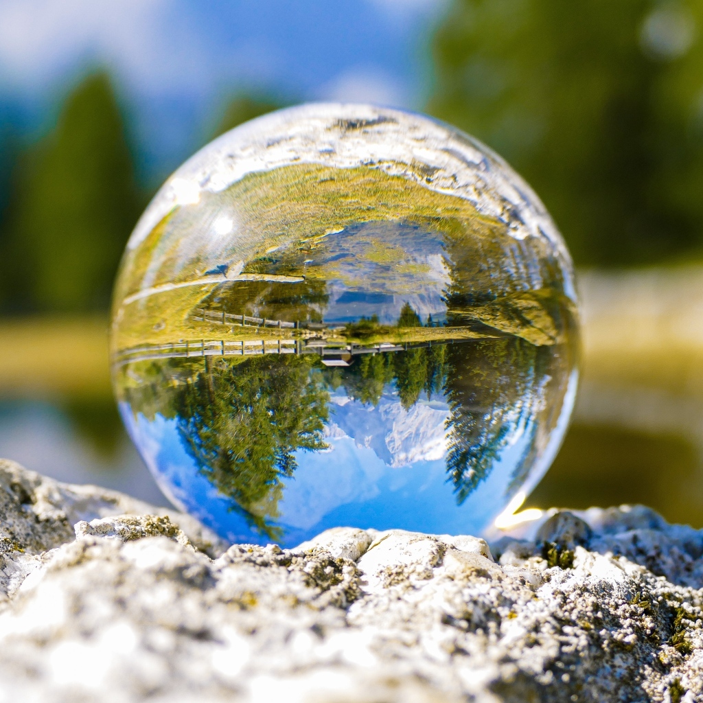 Стеклянный шар стоит на камне у воды