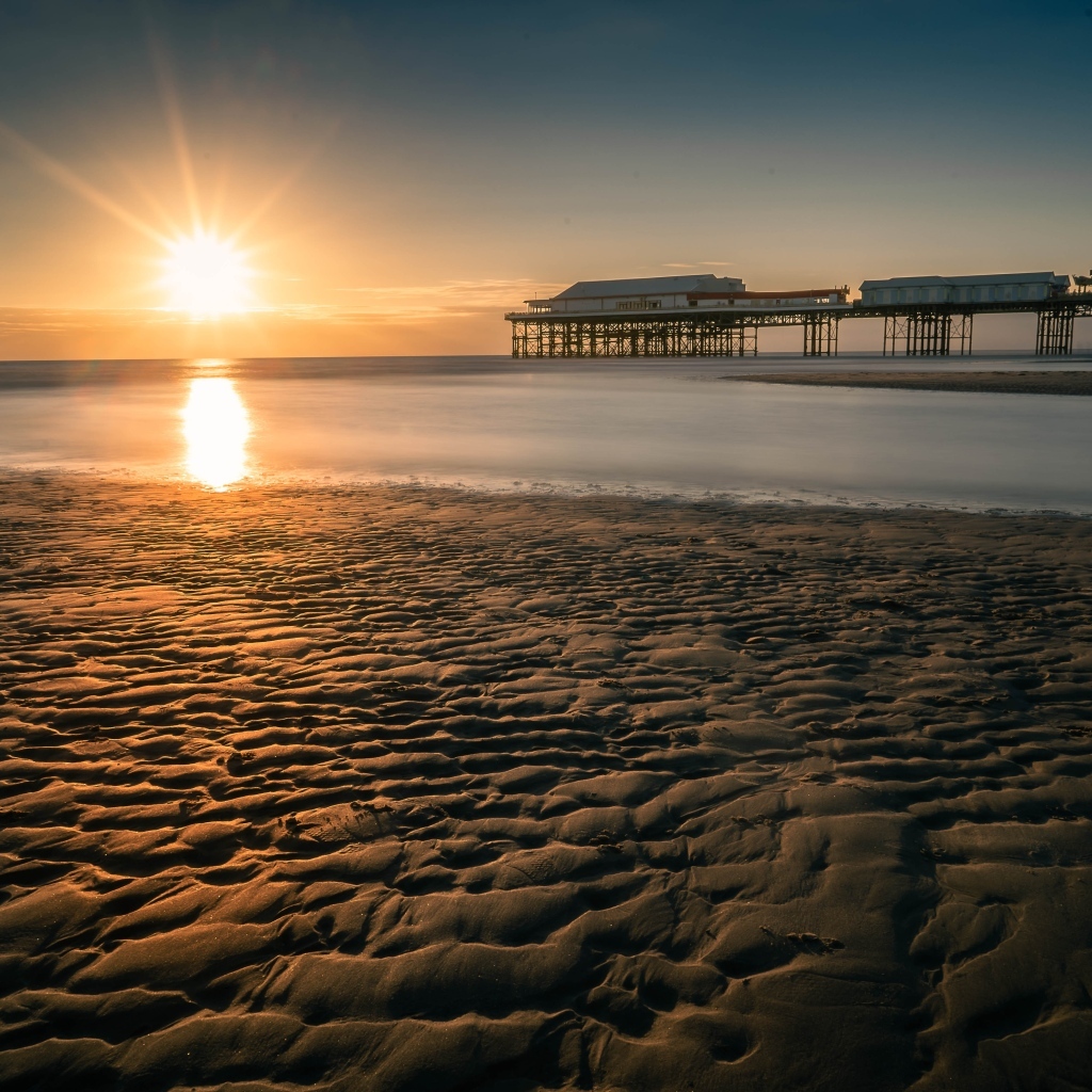 Мокрый песок на берегу моря на закате