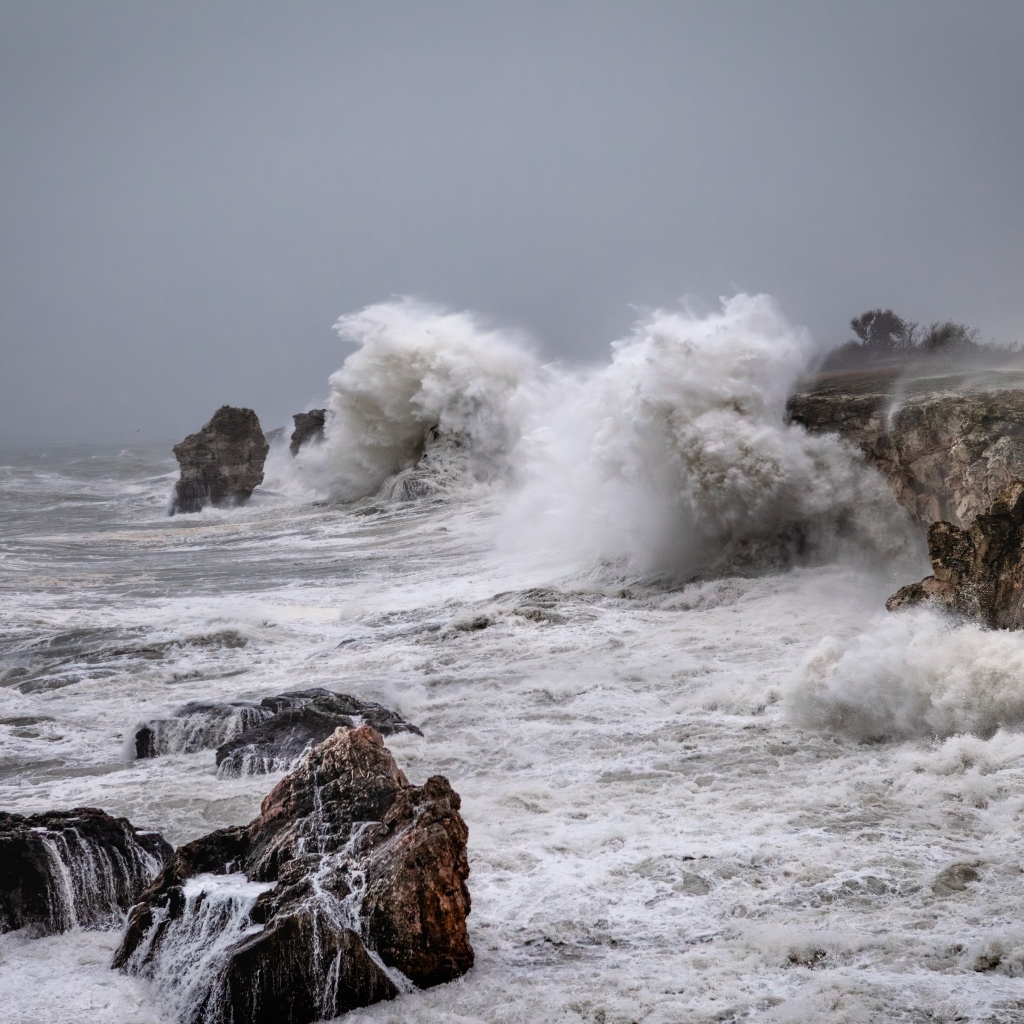 Белые пенные волны бьются об камни во время шторма