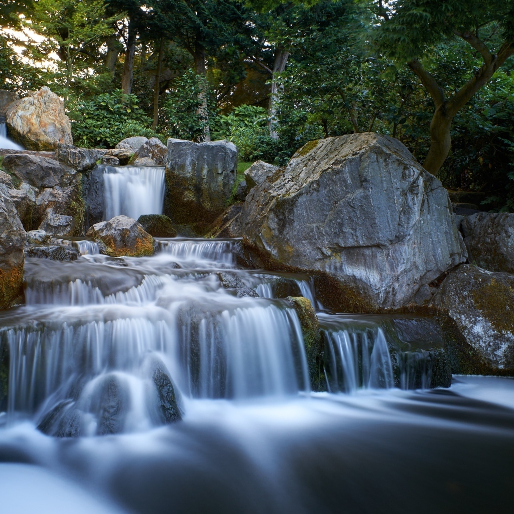 Водопад стекает по большим холодным камням в лесу