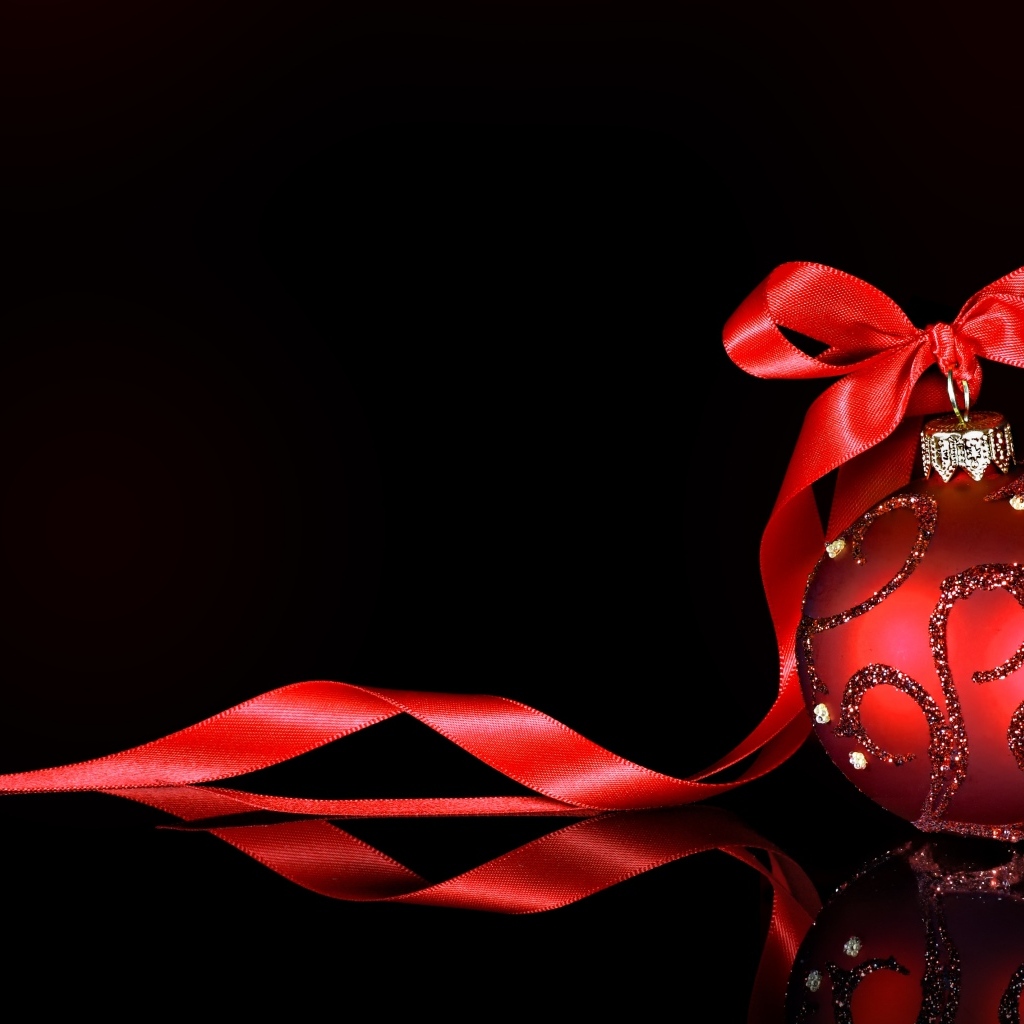 Красный елочный шар с лентой на черном фоне