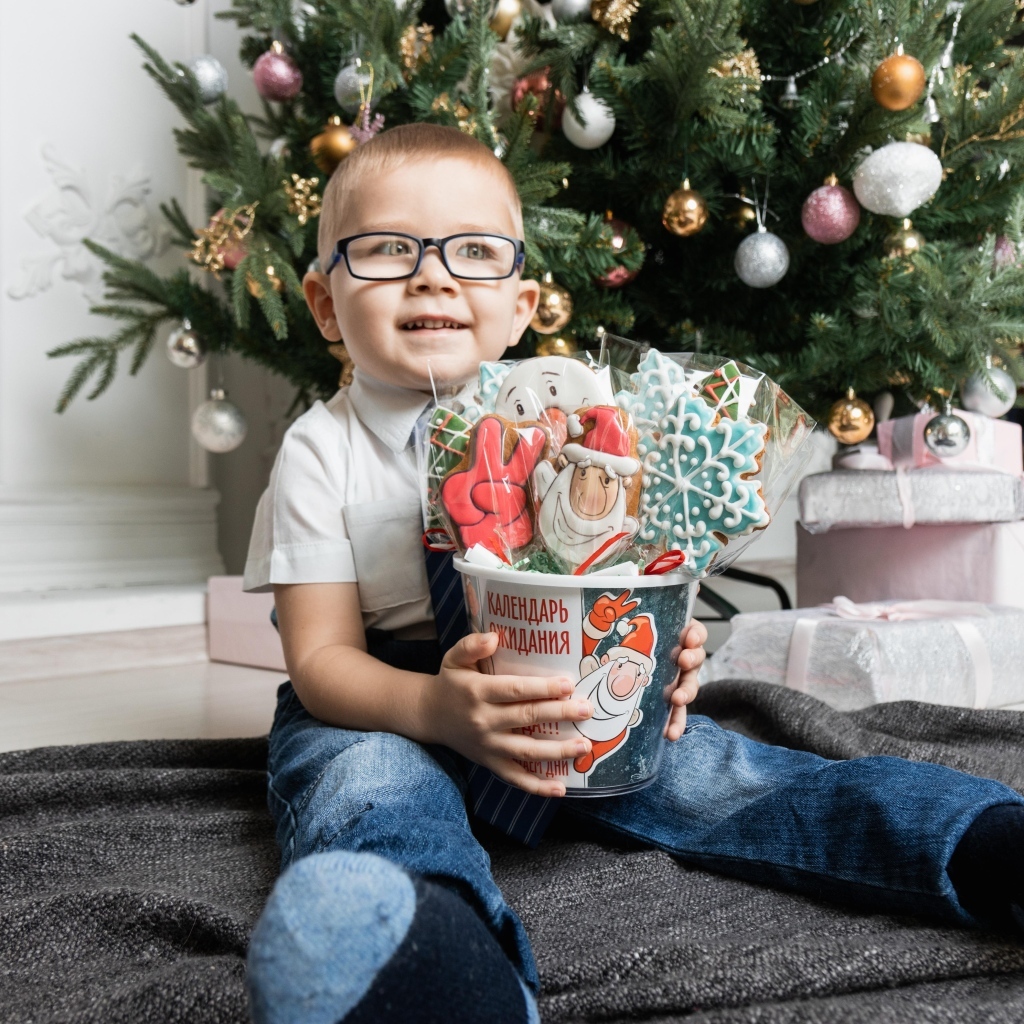 Маленький мальчик с печеньем сидит у ели