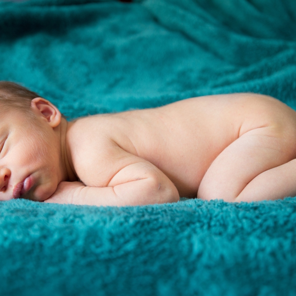 Грудной ребенок спит на синем пледе