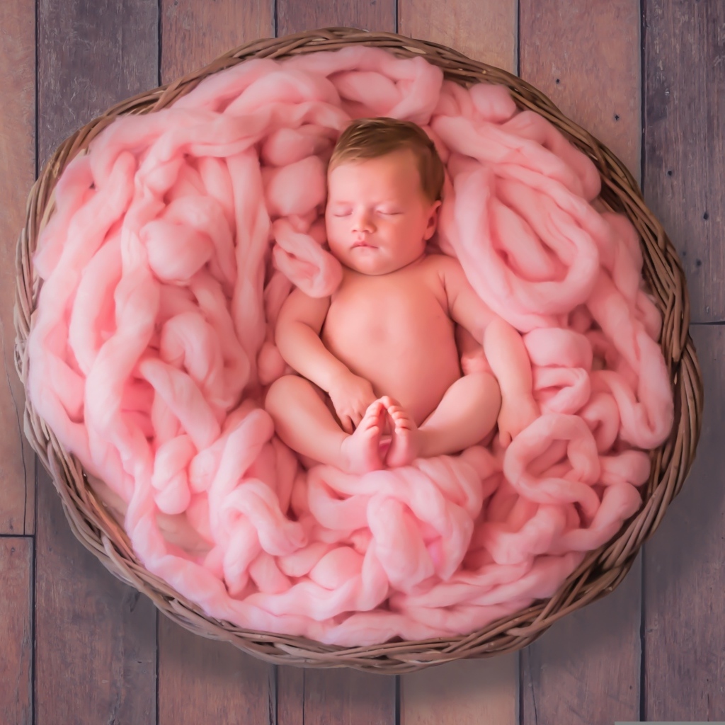 Ребенок спит в корзине с розовым покрывалом