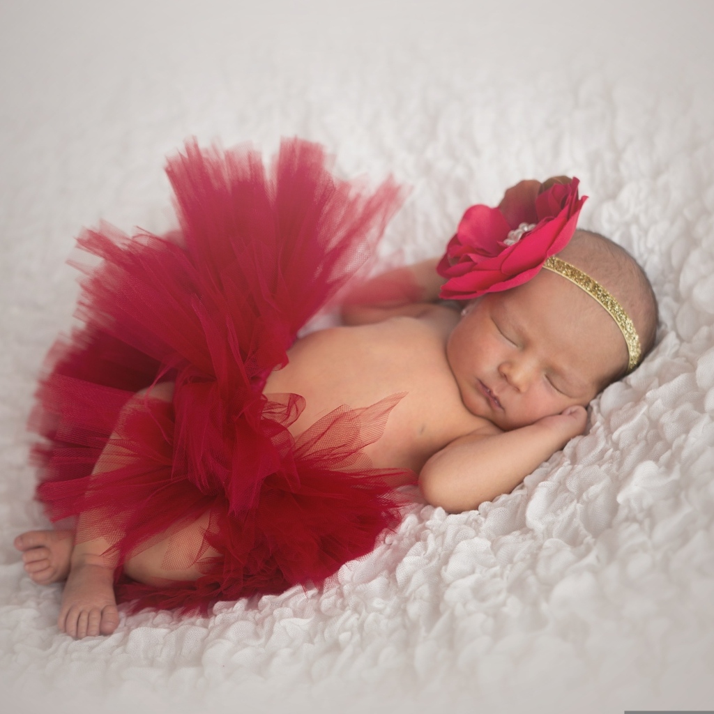Красивая пышная красная юбка и бант на спящей малышке