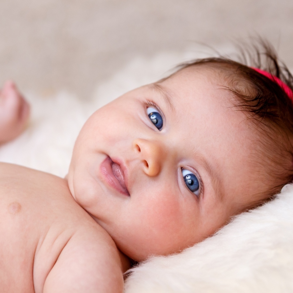 Голубоглазая новорожденная малышка с цветком на голове