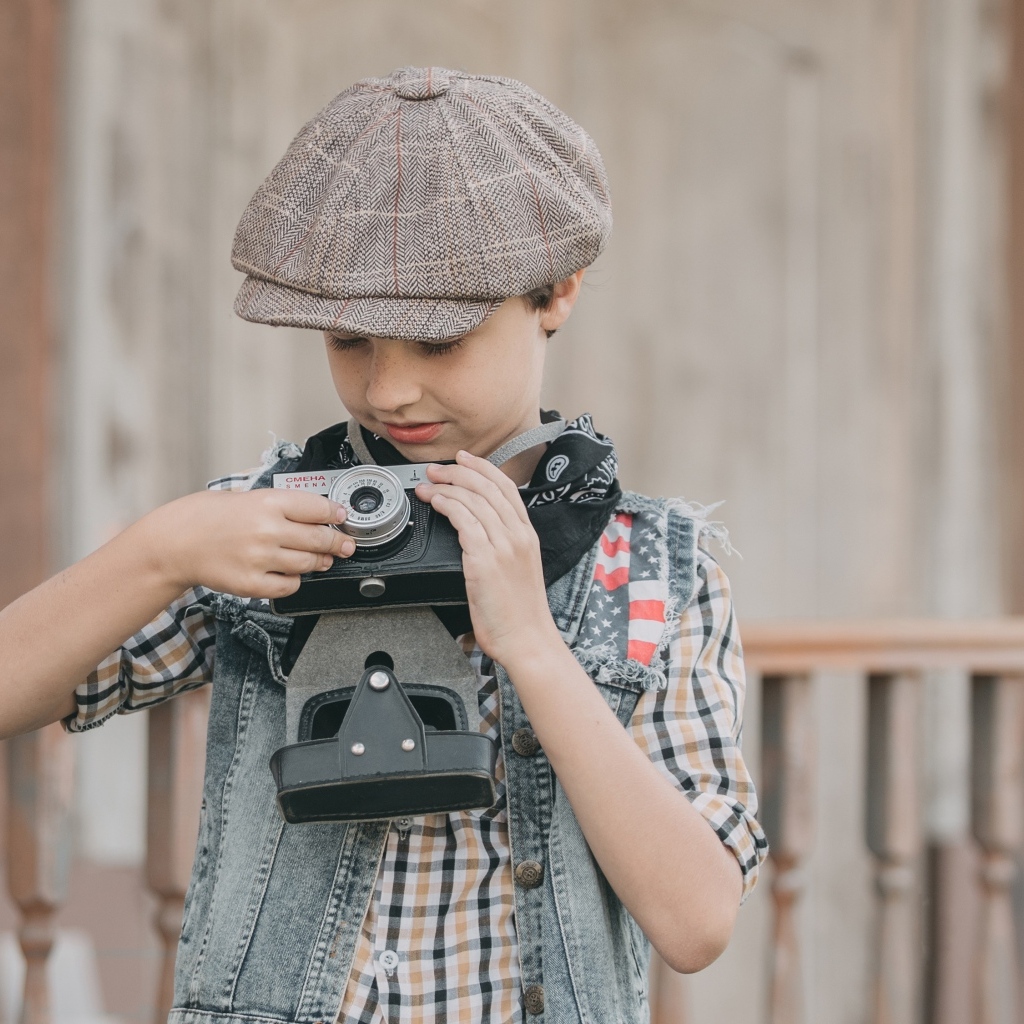 Мальчик в кепке с фотоаппаратом в руках
