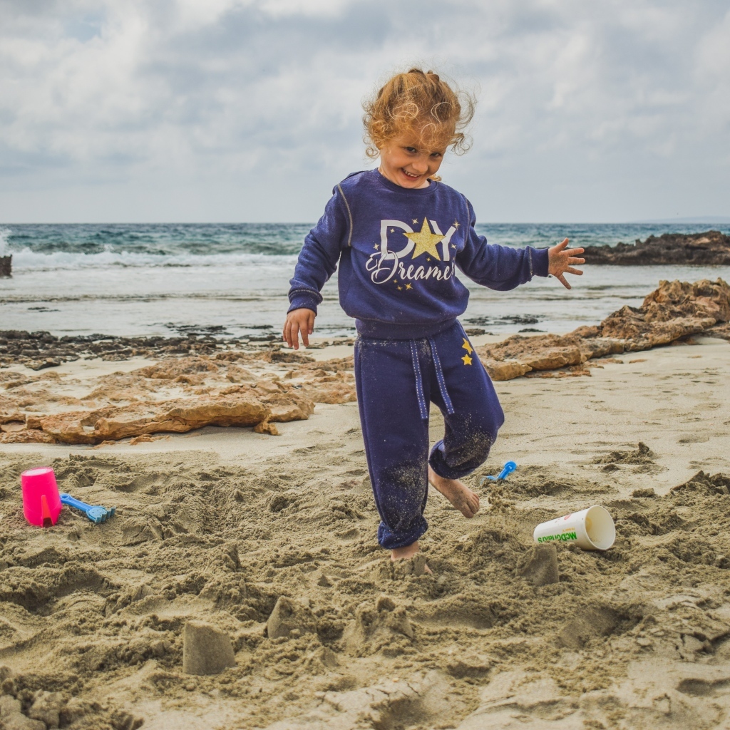 Веселая девочка играет на песке на пляже