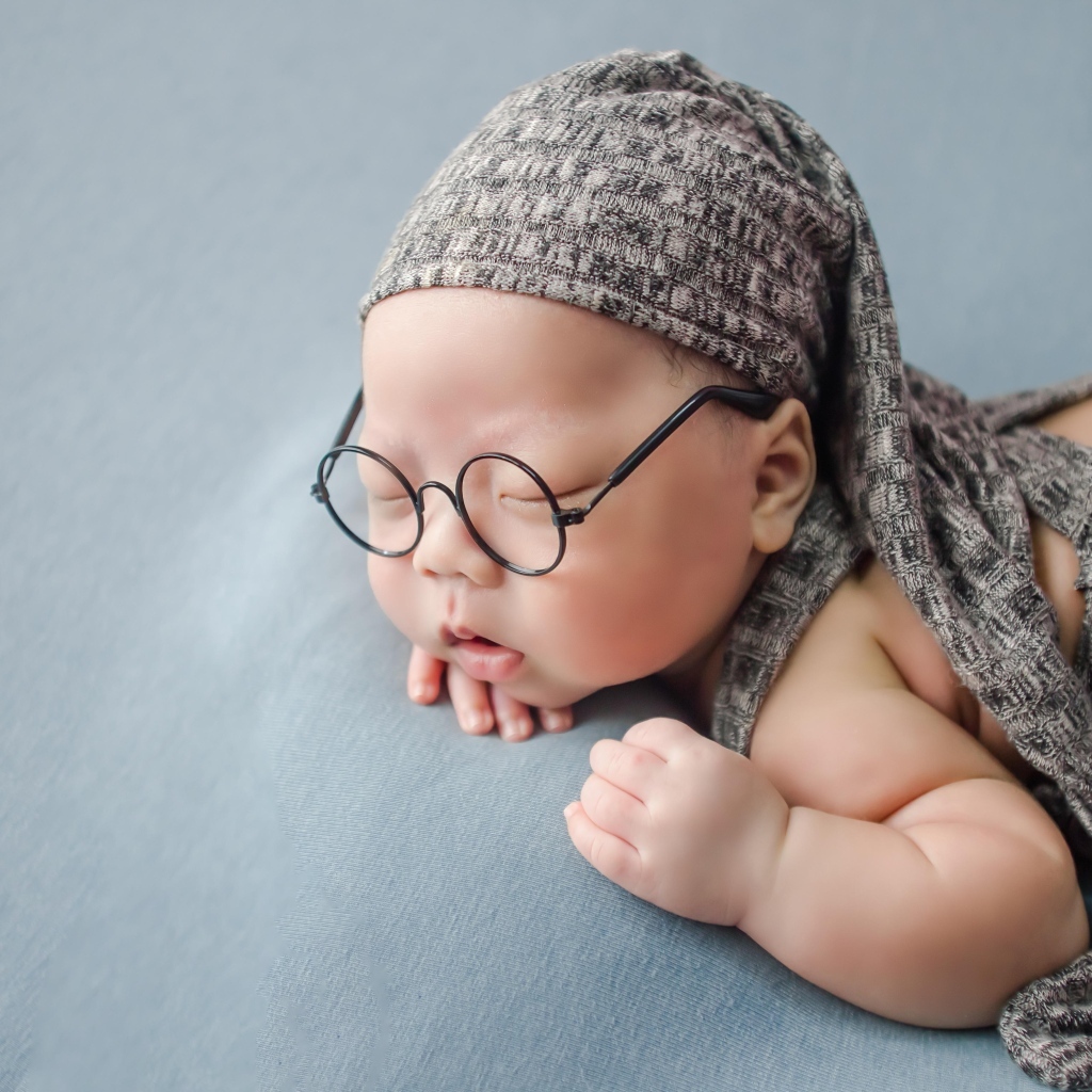 Забавный малыш в очках одет в серый костюм