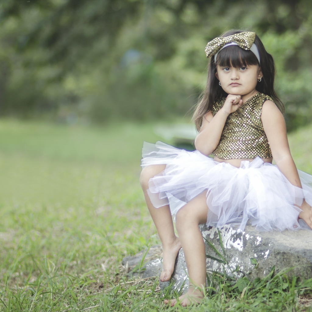 Девочка в красивом платье сидит на камне