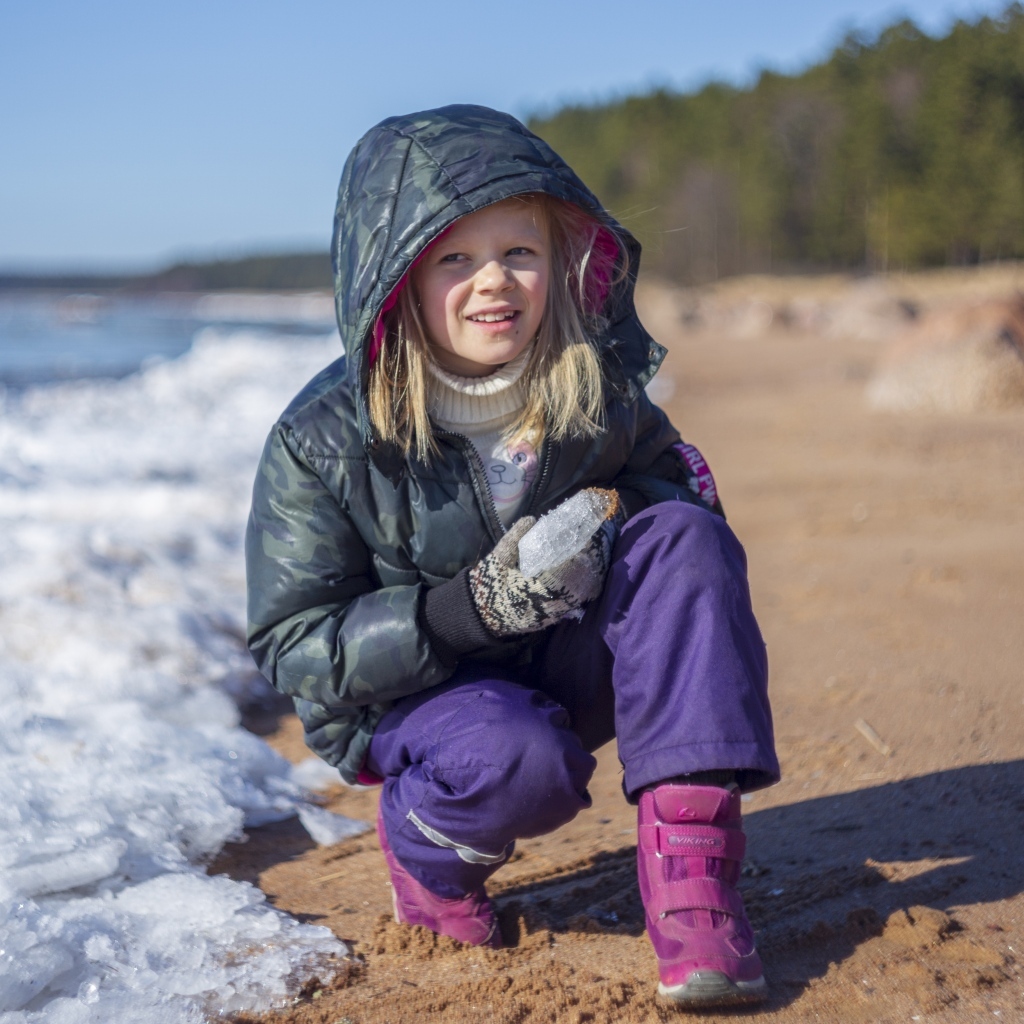 Девочка сидит у замерзшего озера 