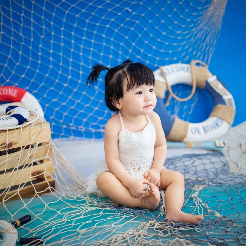 Маленькая девочка азиатка со  спасательным кругом и сетью 