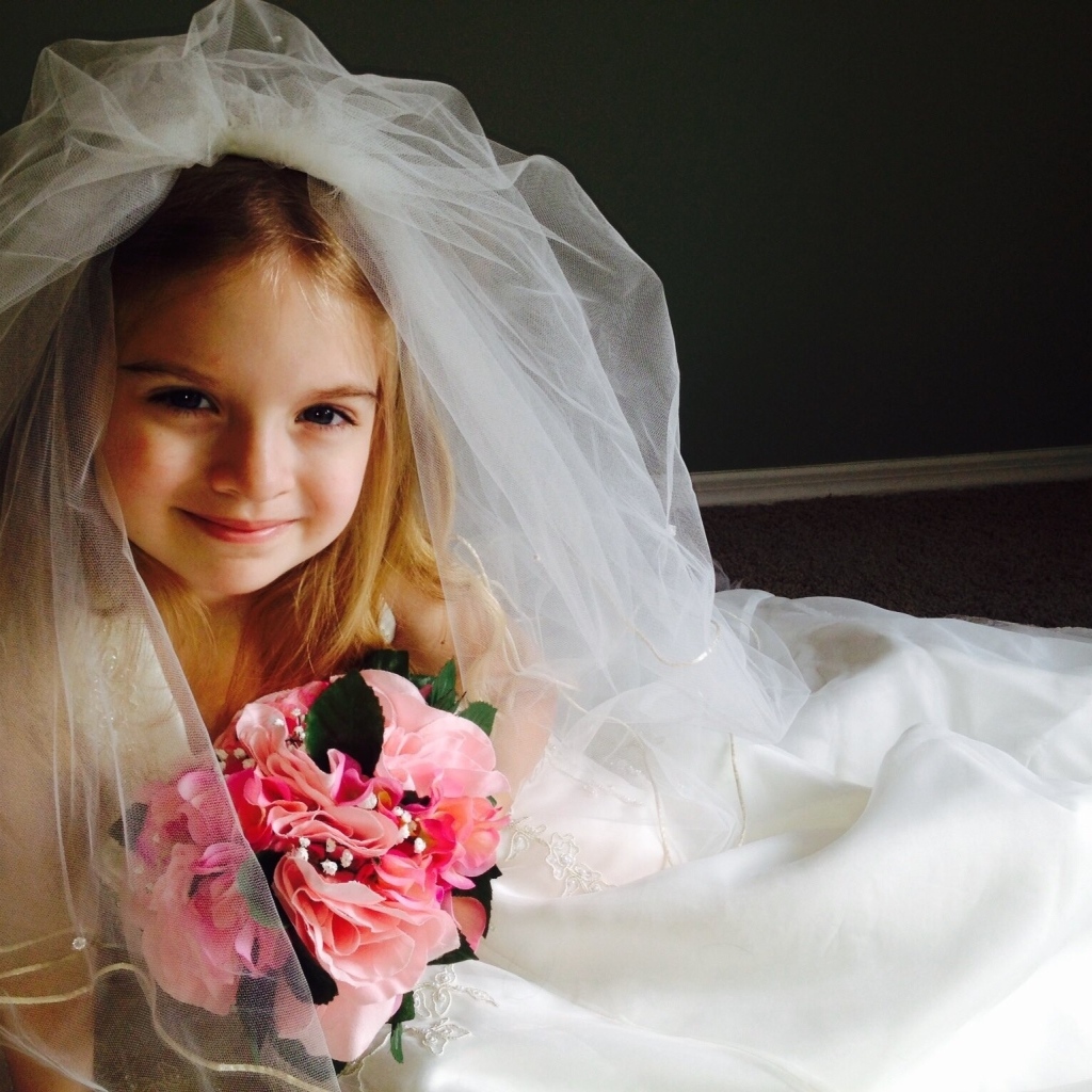 Маленькая девочка в костюме невесты с букетом