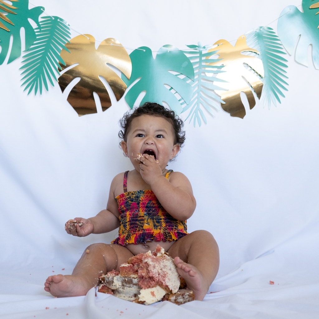 Маленькая девочка ест торт на белом фоне