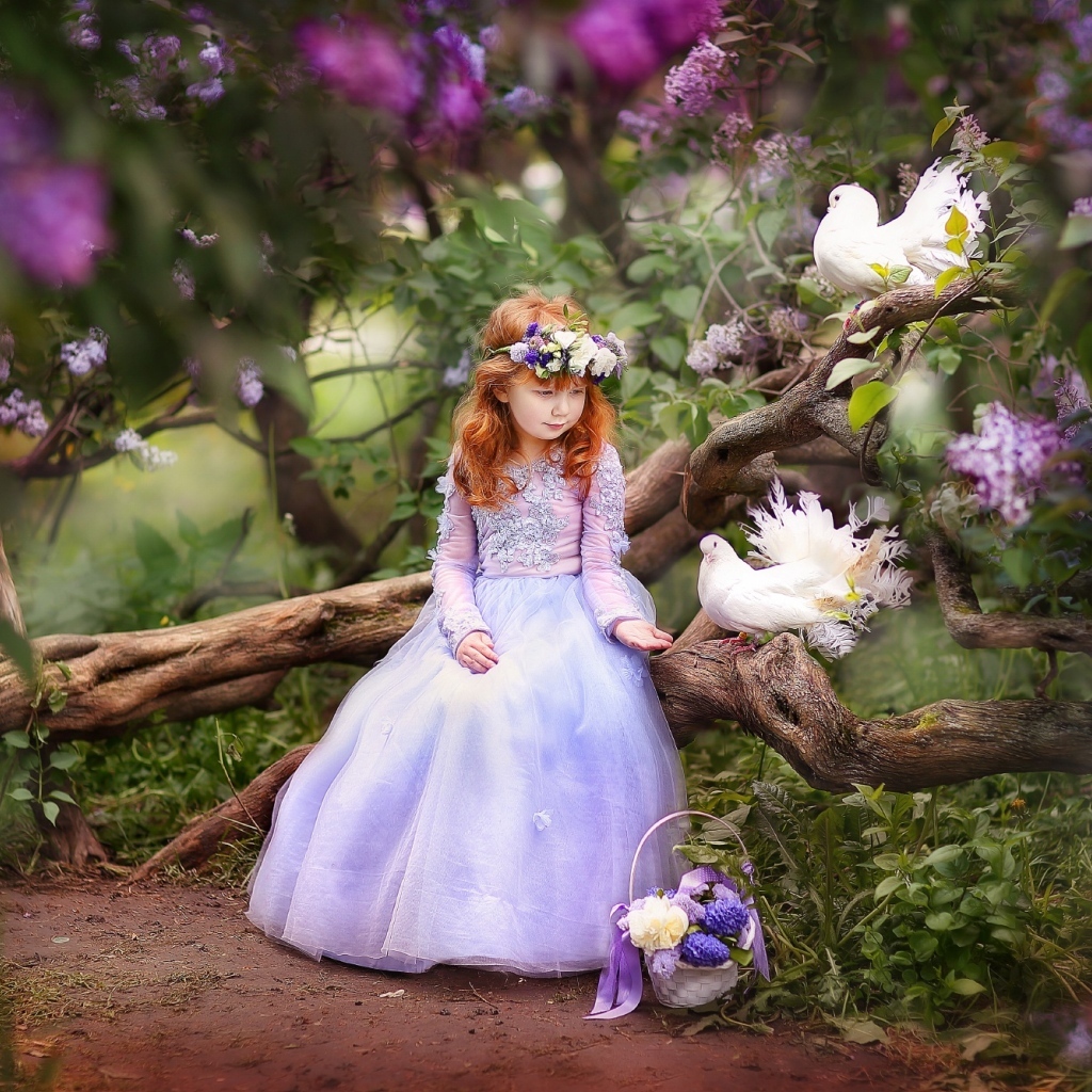 Маленькая девочка в красивом платье на дереве с голубями