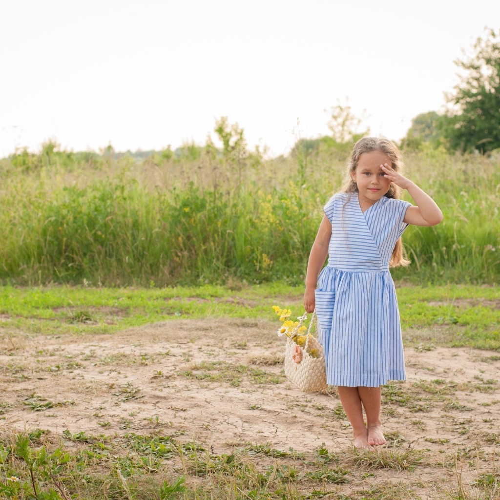 Маленькая девочка в платье с корзиной полевых цветов