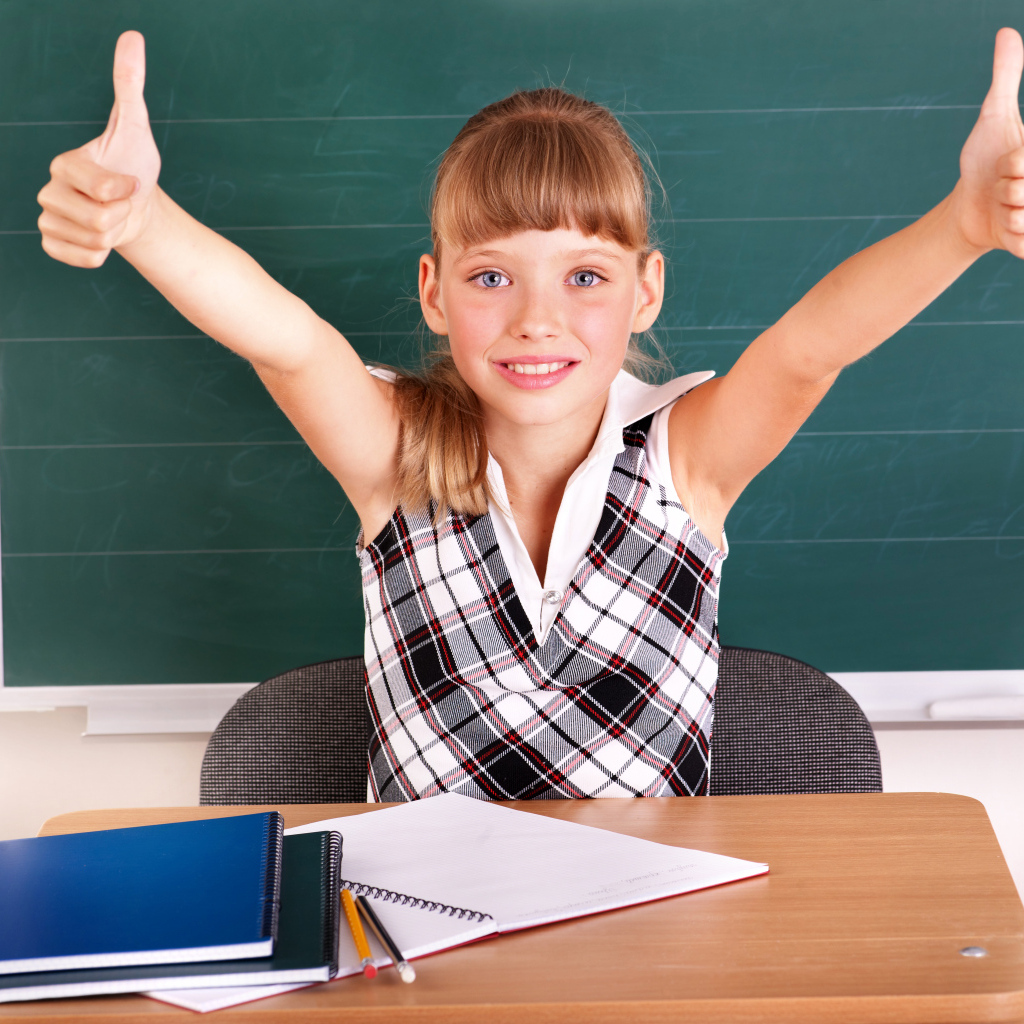 Маленькая девочка школьница в классе за партой 