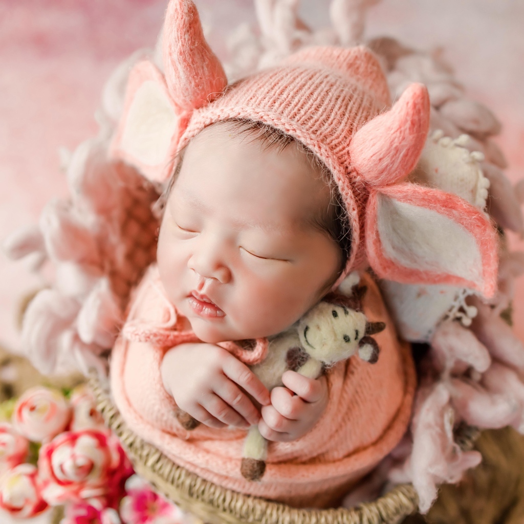 Маленький спящий новорожденный ребенок в шапке с рогами