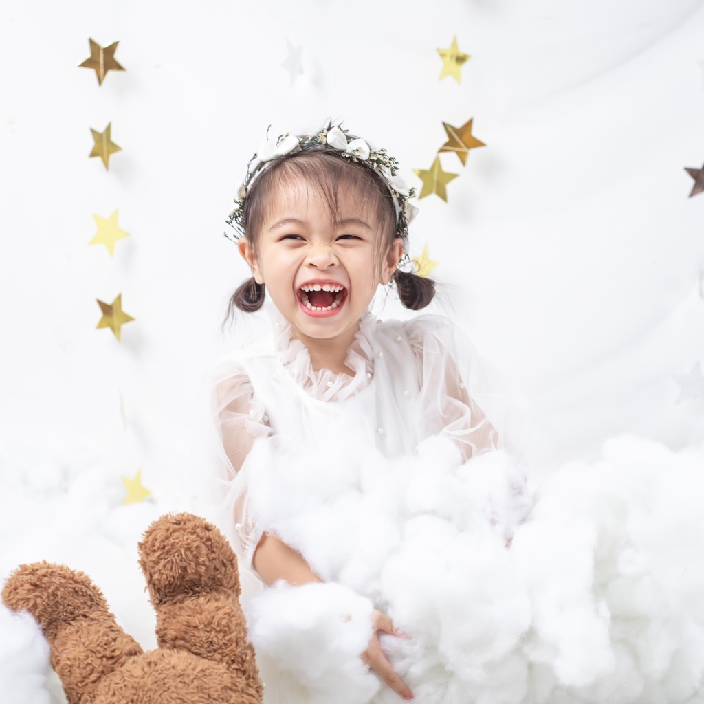 Маленькая улыбающаяся девочка азиатка в белом платье