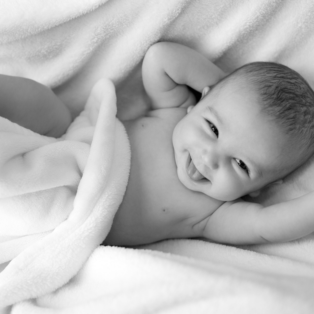 Маленький улыбающийся ребенок в белом покрывале