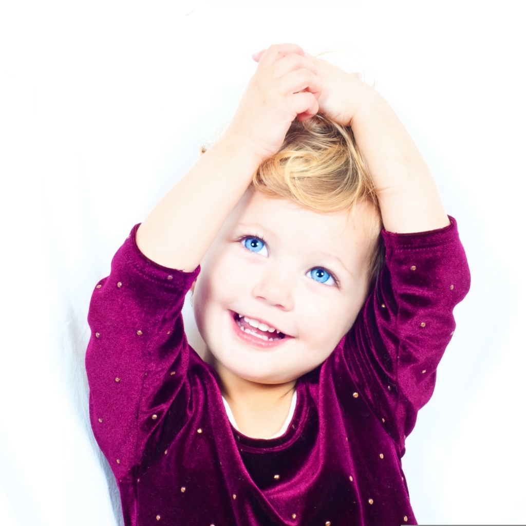 Маленькая улыбающаяся голубоглазая девочка на белом фоне