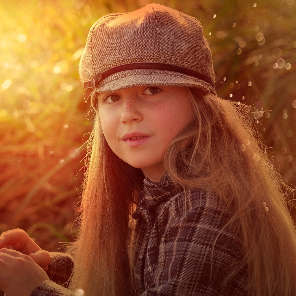 Длинноволосая девочка в кепке в лучах солнца