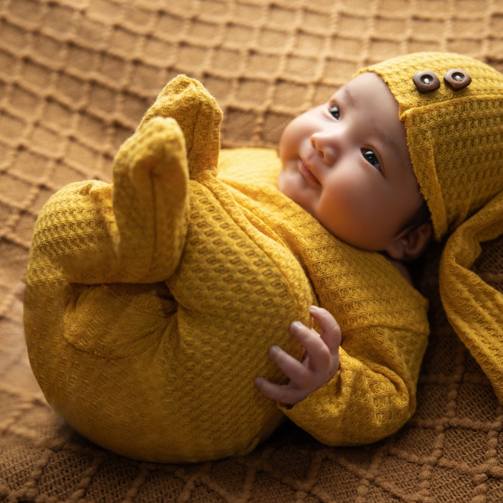 Новорожденный ребенок в желтом костюме 
