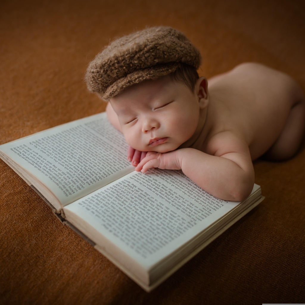 Новорожденный малыш спит на книге