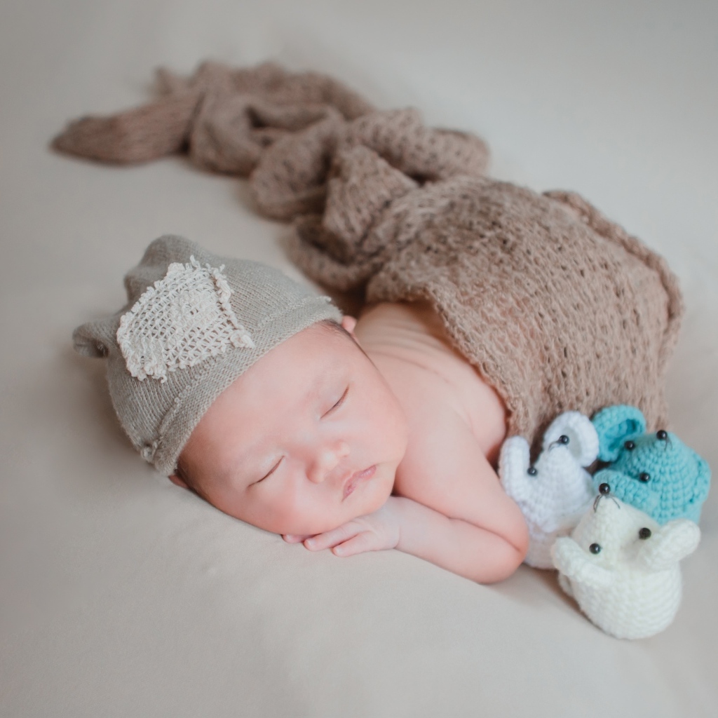 Новорожденный малыш спит на сером покрывале
