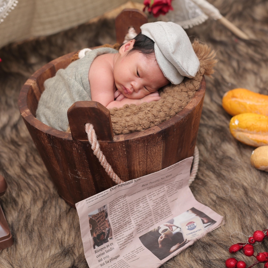 Новорожденный маленький мальчик в деревянном ведре на фотосессии 