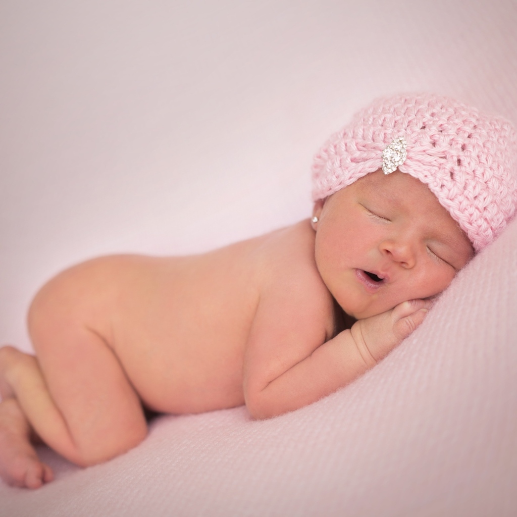 Розовая шапка на голове новорожденной девочки
