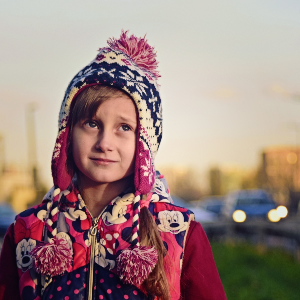 Грустная девочка в теплой шапке на улице