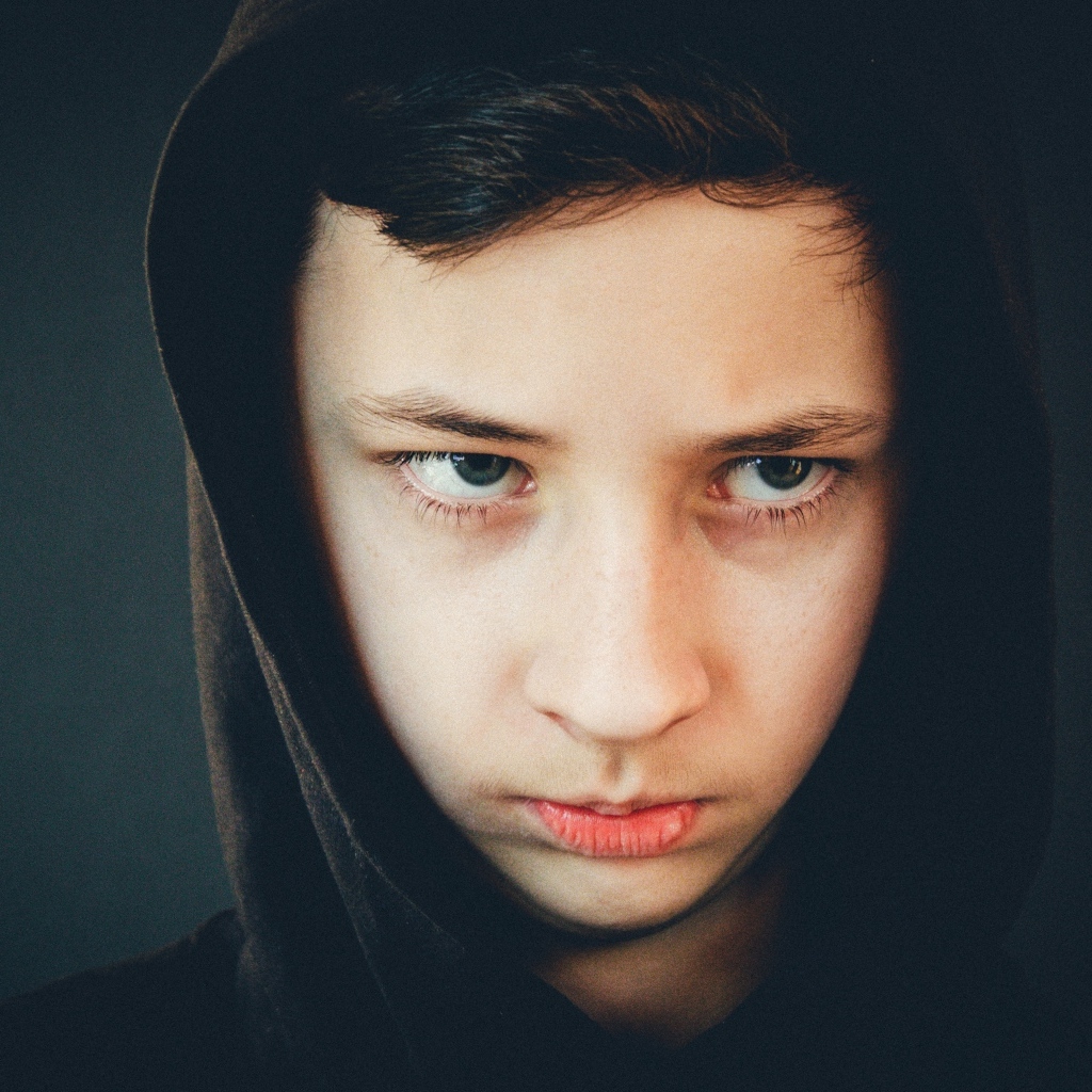 Серьезный мальчик в черном капюшоне