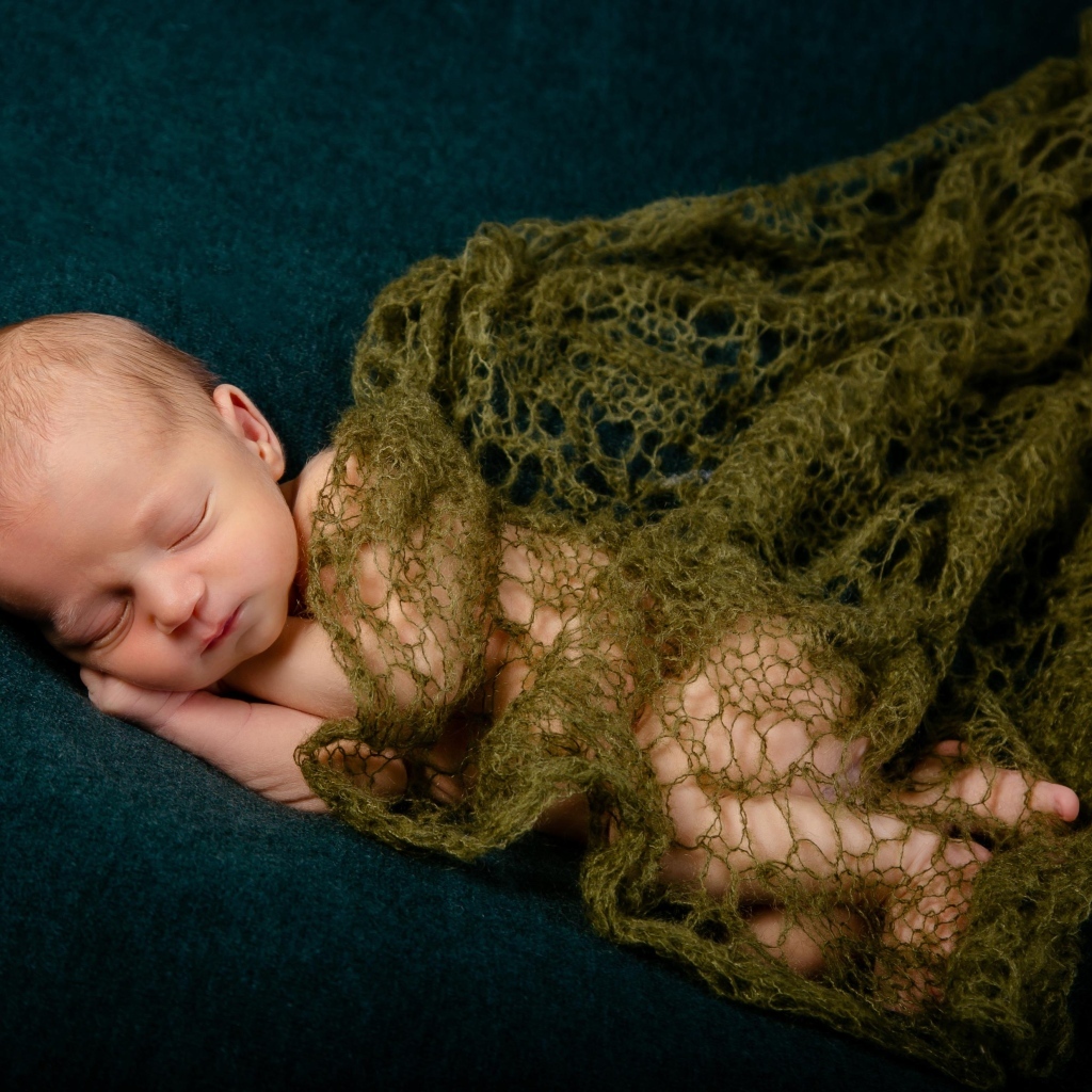 Спящий новорожденный ребенок укрыт шалью