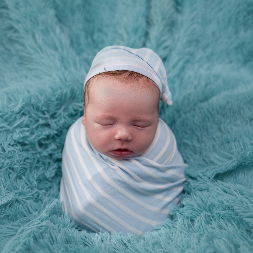 Спящий новорожденный малыш на голубом покрывале 