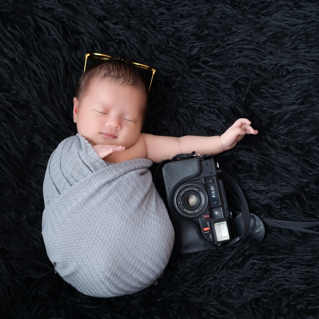 Спящий новорожденный малыш с фотоаппаратом