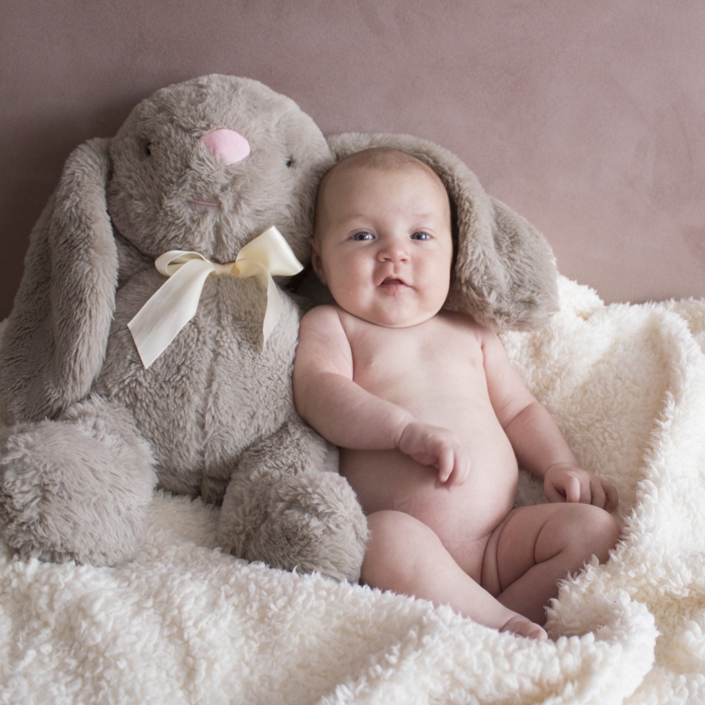 Улыбающийся малыш с игрушечным зайцем
