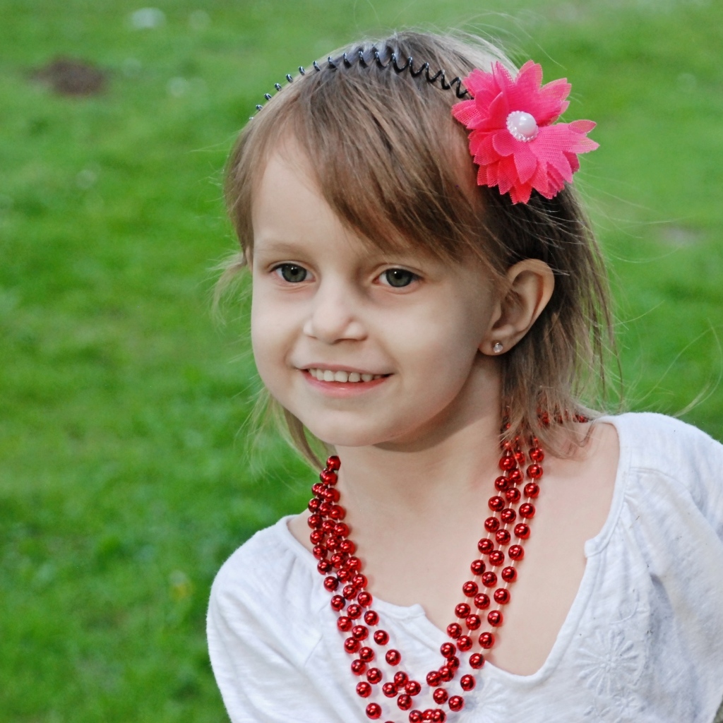 Улыбающаяся девочка стоит у дерева