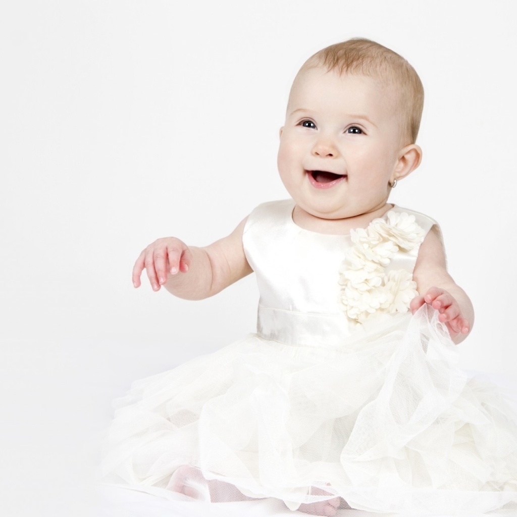 Улыбающаяся маленькая девочка в белом платье 