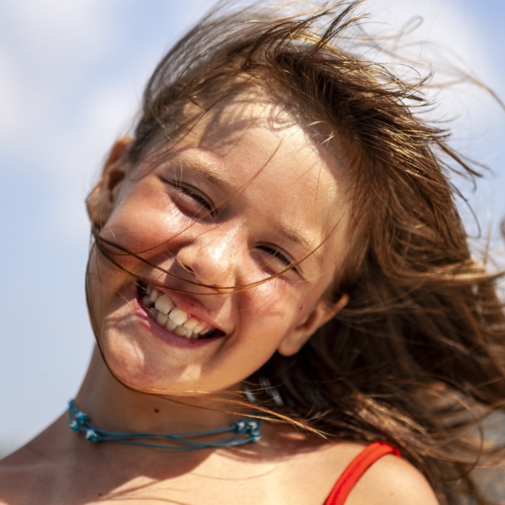 Улыбающаяся маленькая девочка стоит на ветру