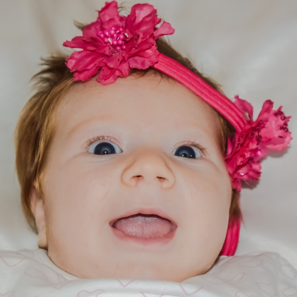 Улыбающаяся маленькая девочка с цветком на голове