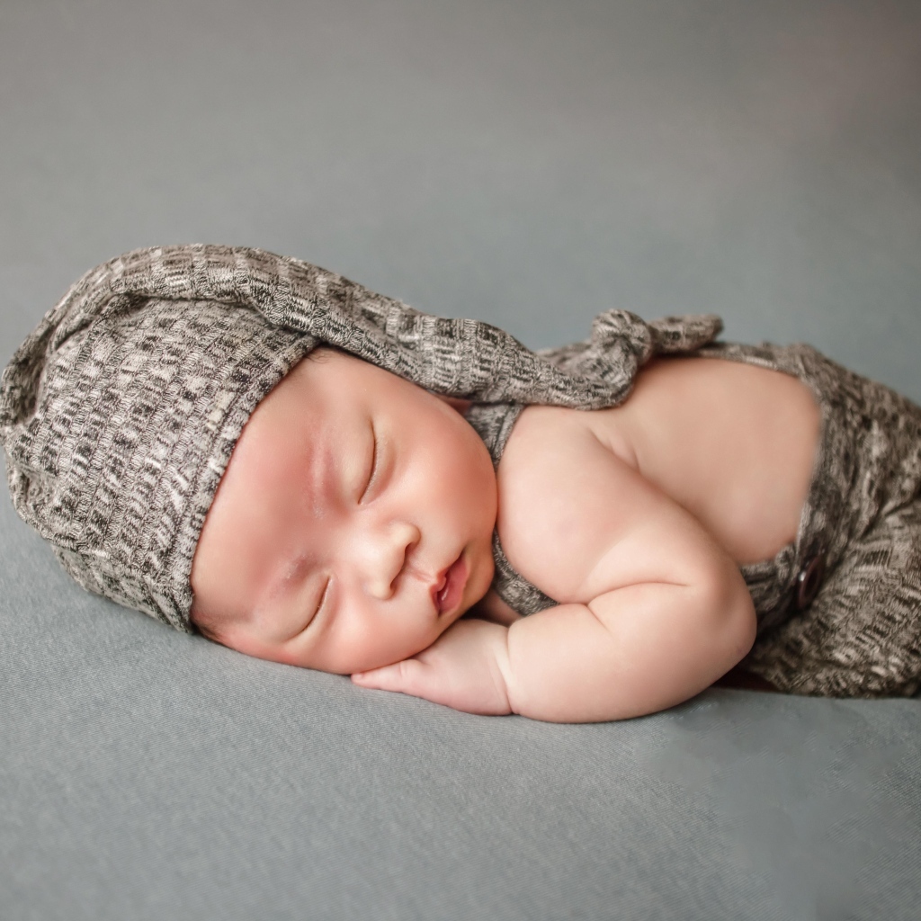 Ребенок спит в костюме на сером покрывале