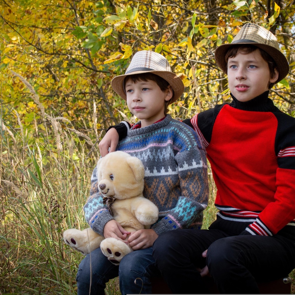 Два мальчика с игрушкой сидят у дерева