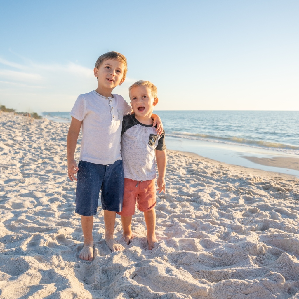 Два маленьких мальчика стоят на песке у моря