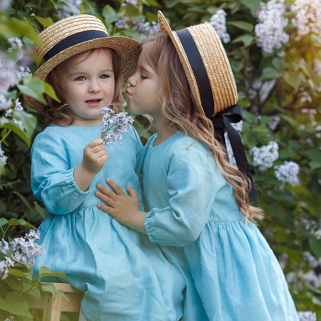 Две маленькие девочки в саду с сиренью