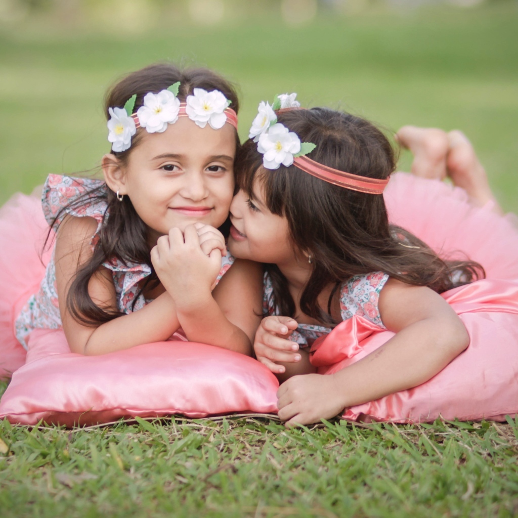 Две маленькие девочки лежат на подушках на траве