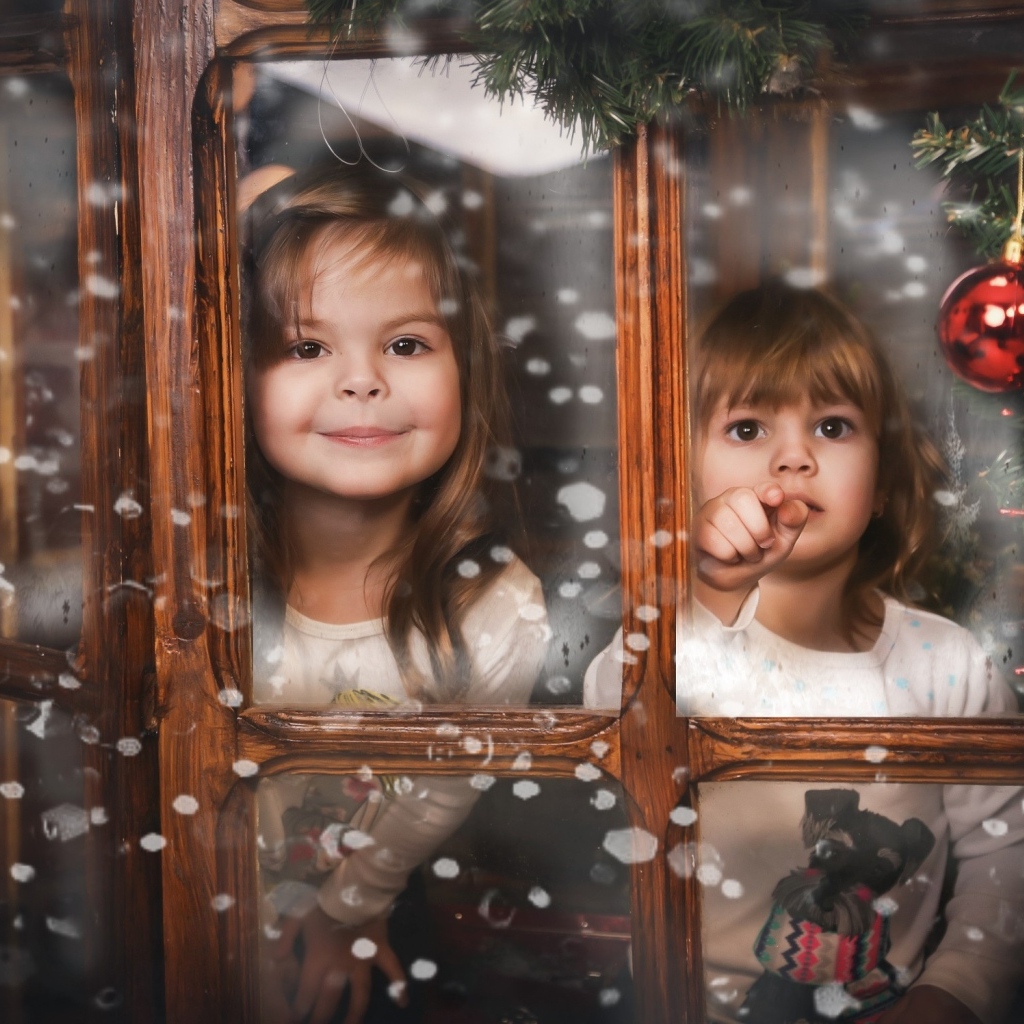 Две маленькие девочки сидят у окна на Рождество
