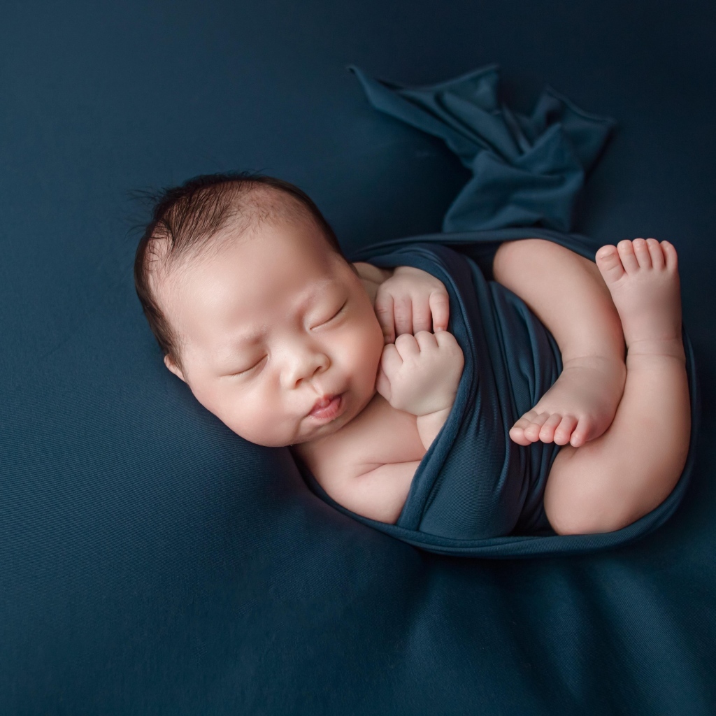 Новорожденный малыш в черном покрывале