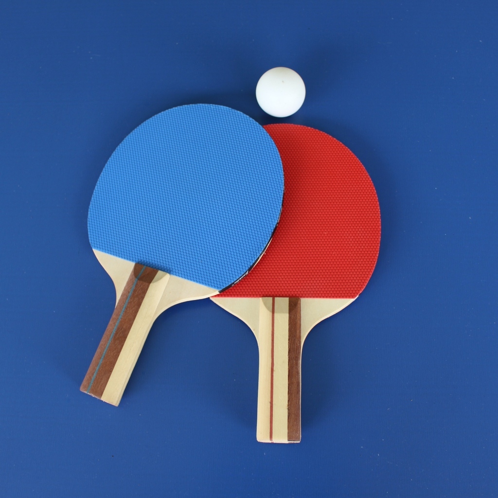 Две разноцветные ракетки и мяч для настольного тенниса