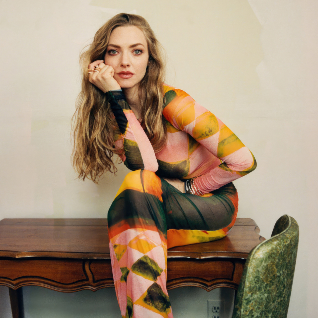 Актриса Аманда Сайфред в платье сидит на столе